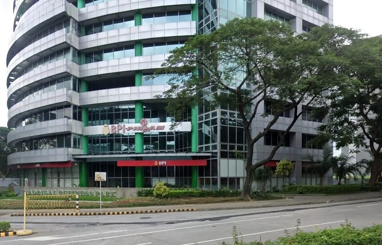 Exterior view of the BPI-Philam and BPI Alabang Ayala Life Branch office, a multi-story modern building with green accents and large trees in front