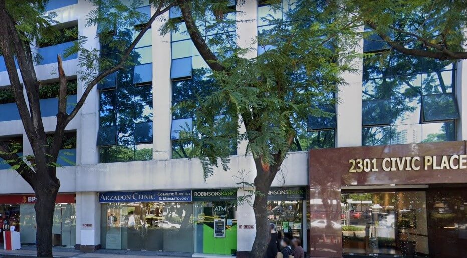 The exterior of the building at 2301 Civic Place features large glass windows partially shaded by trees. The ground-floor storefront includes the Arzadon Clinic, Robinsons Bank, and BPI branches
