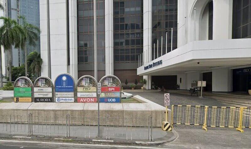 Ground-level view of the Pacific Star Building entrance in Makati, featuring a row of arched directory signs for tenants including BPI, FWD, and Century Properties, with a white canopy over the driveway