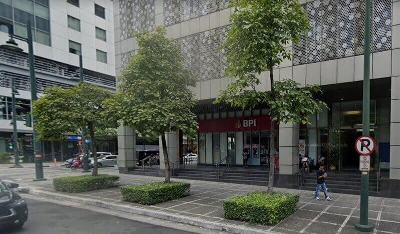 Exterior view of a BPI bank branch at the corner of 30th Street in BGC, featuring a red storefront sign, glass windows, and sidewalk trees