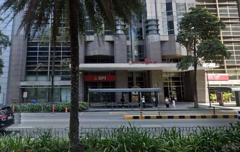 Street-level view of the BPI Ayala East Office entrance in Makati, featuring the red BPI logo above a glass storefront with pedestrians on the sidewalk