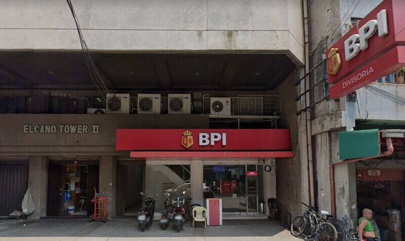 Street-level view of a BPI (Bank of the Philippine Islands) Divisoria branch located on the ground floor of Elcano Tower II, featuring the red BPI signage, a glass storefront, and parked motorcycles and bicycles outside