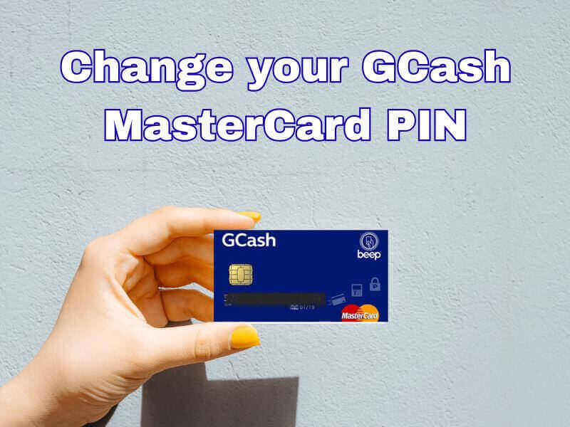 A hand holding a blue GCash MasterCard against a plain grey wall background, with text overlay reading "Change your GCash MasterCard PIN".